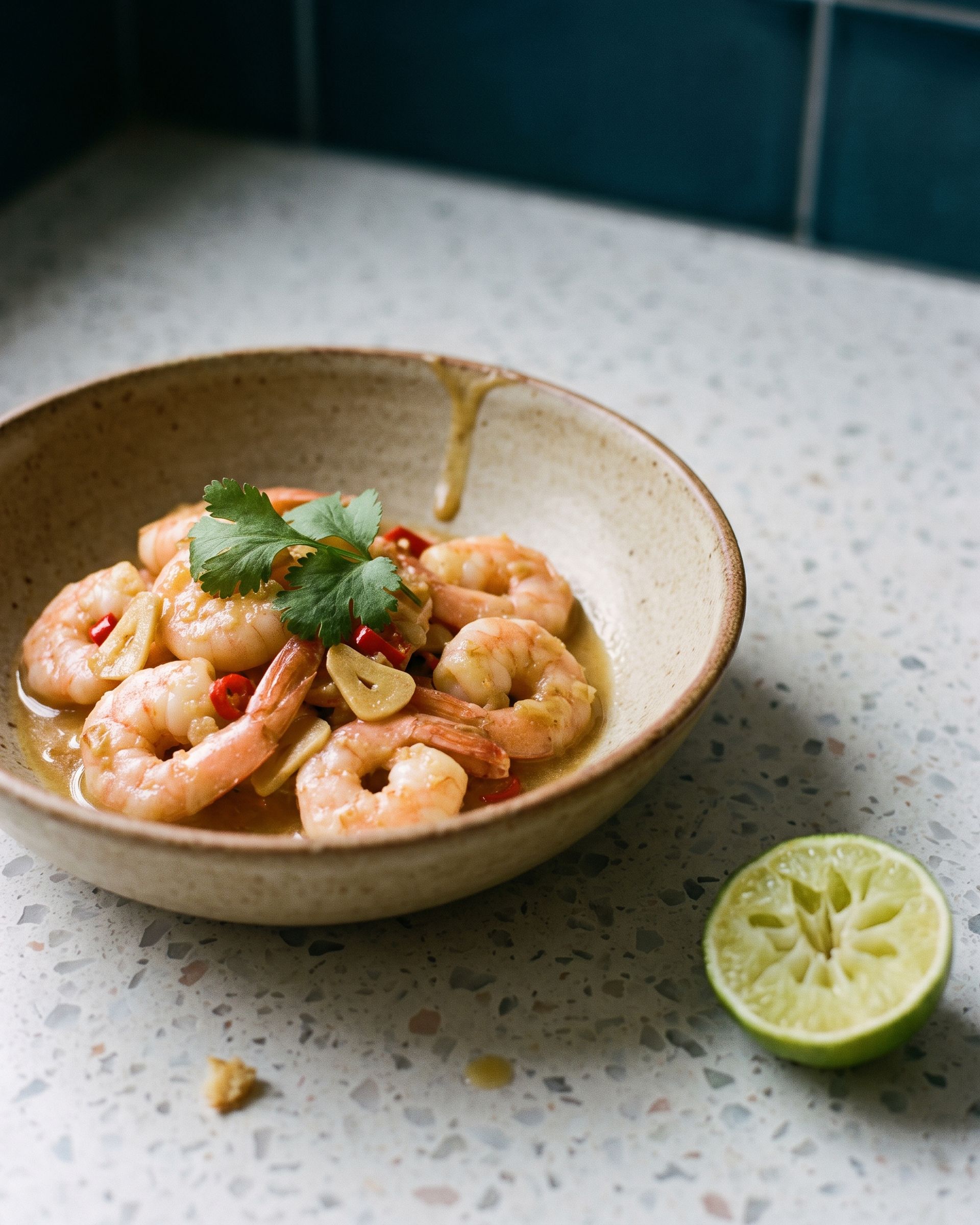 Prawns in a cloudy ginger sauce with sliced red chilli and coriander, in a sand-glazed bowl