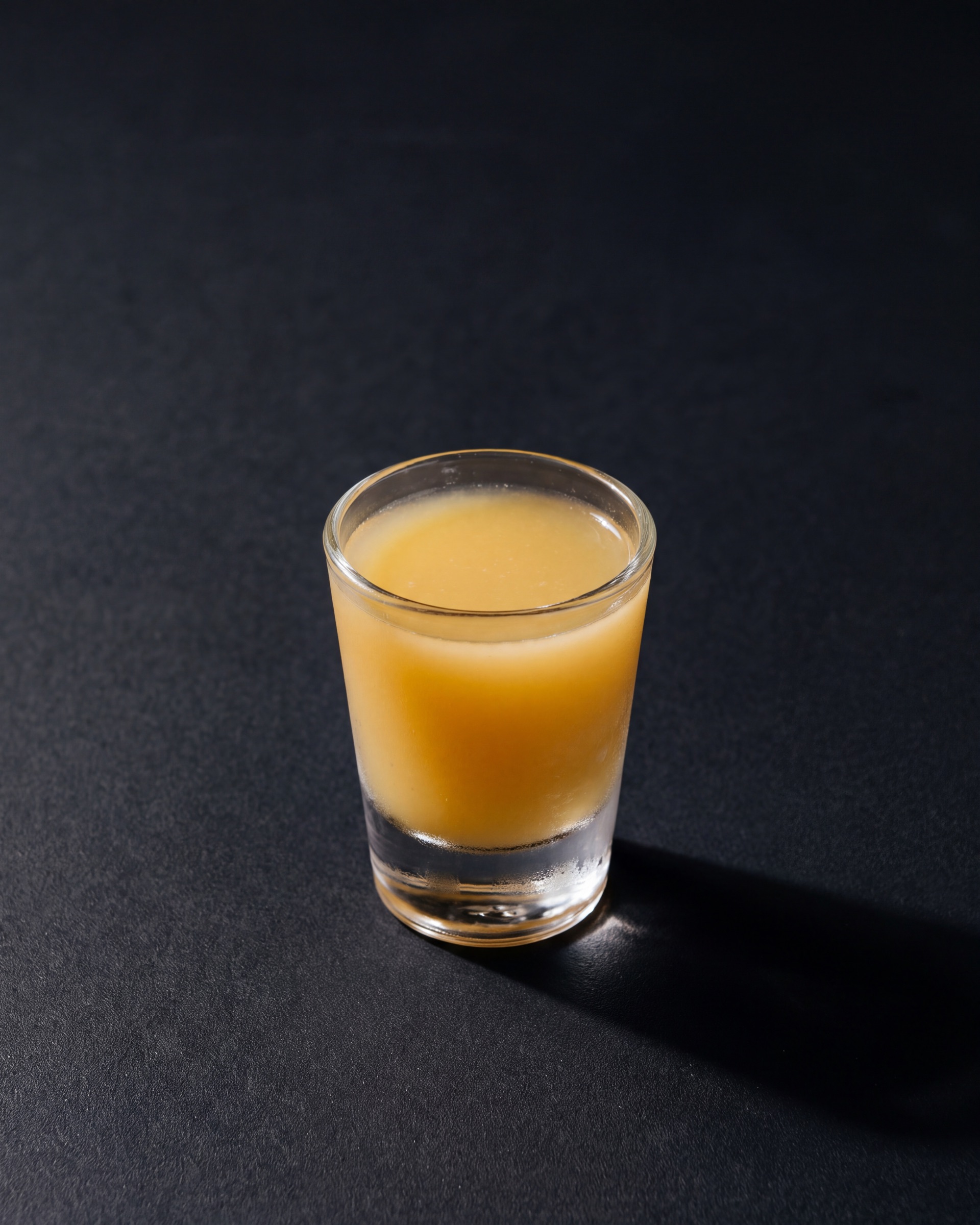 A small glass of deep undiluted kink ginger shot