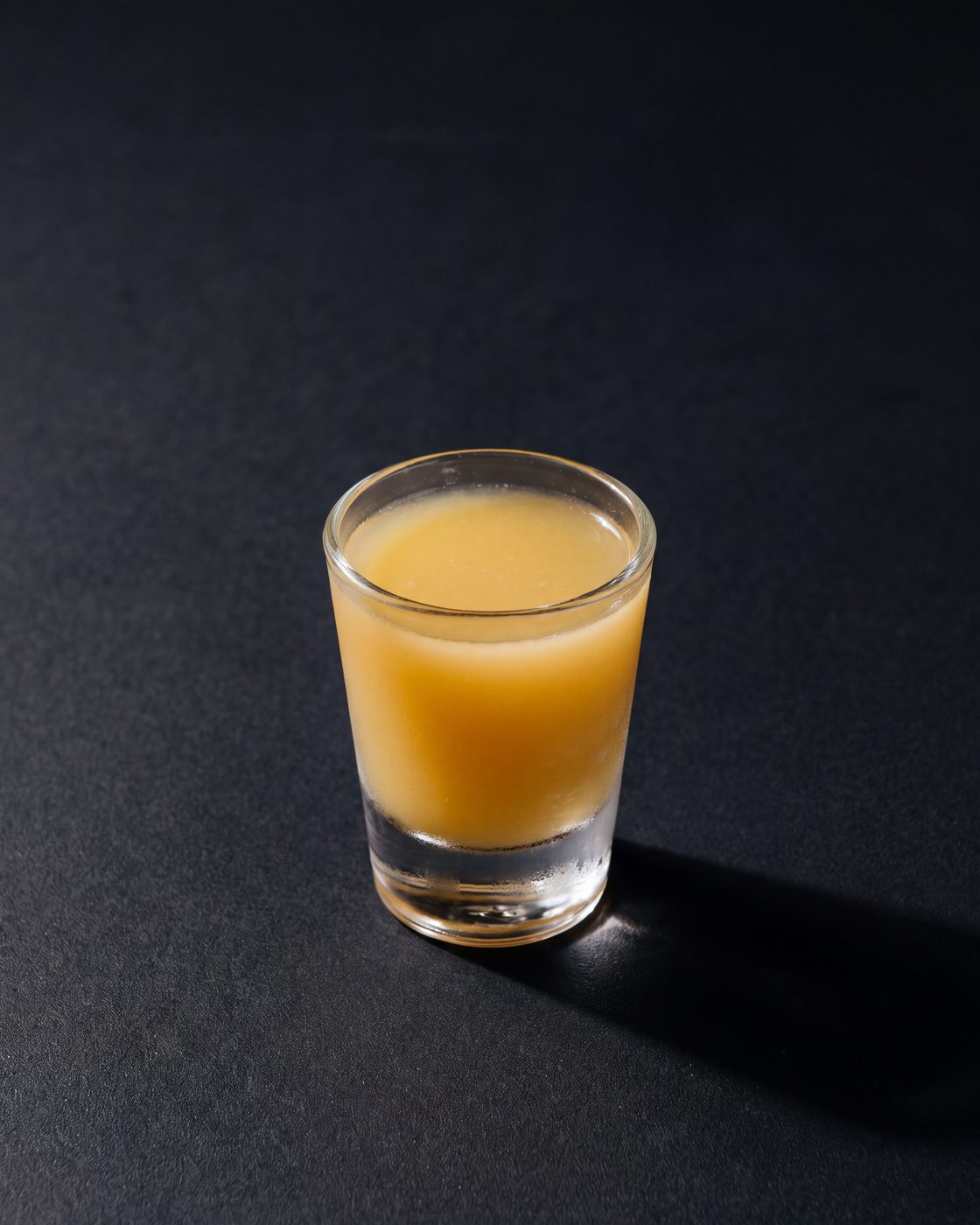 A small glass of deep undiluted kink ginger shot